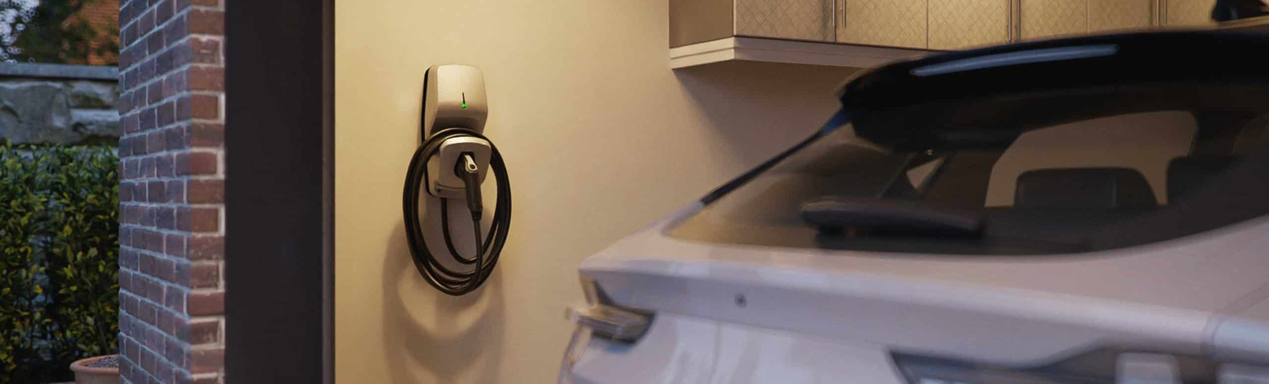 EV charger mounted to the wall of a garage with parked car