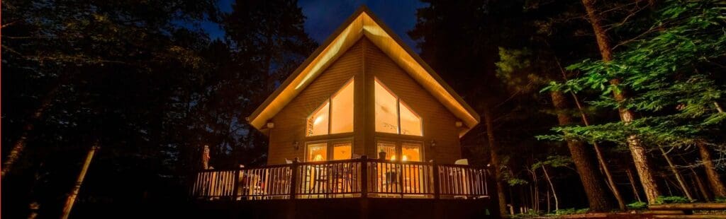 Bright lit up house in the middle of a forest during the night