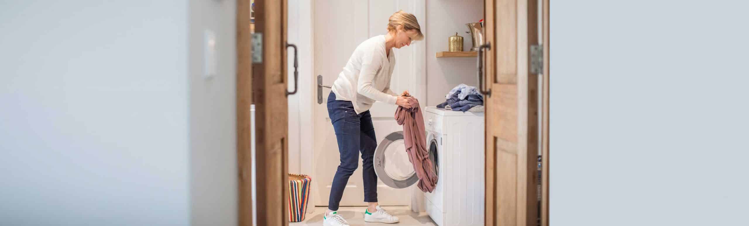 Woman removing clothes from her drying and analysing her clothes with a disappointed look on her face
