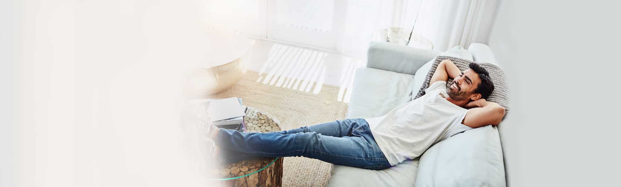 Male laying on sofa with arms crossed at head