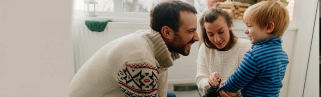 Mother and father kneeling and smiling at their baby