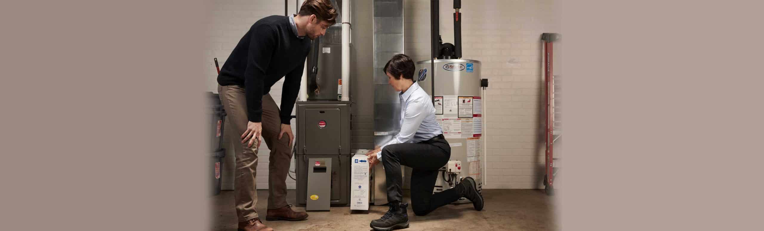 Reliance worker doing furnace maintenance with a client watching by her side
