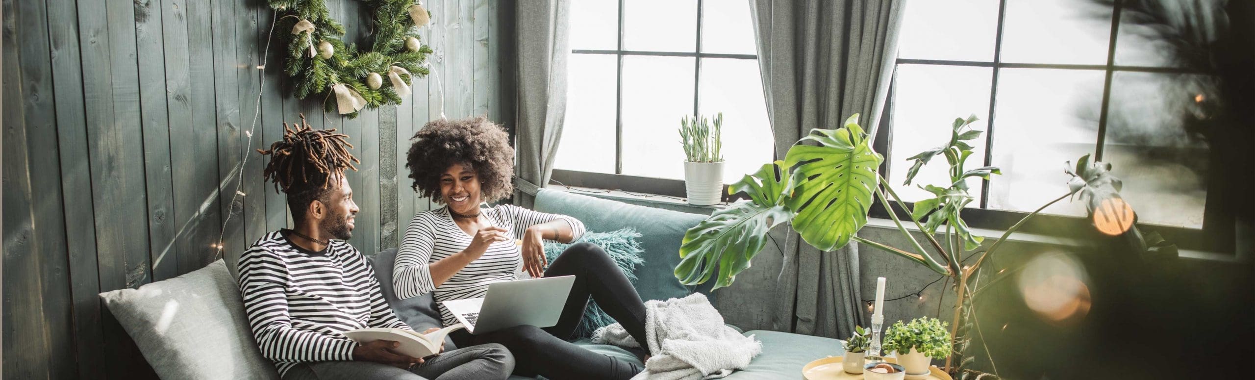 A man and woman sitting on a couch at their home and talking.