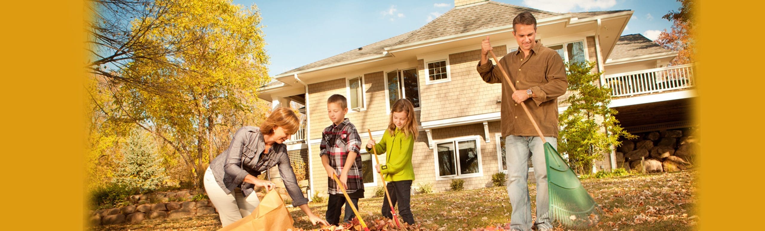 Family raking leaves outside of their home