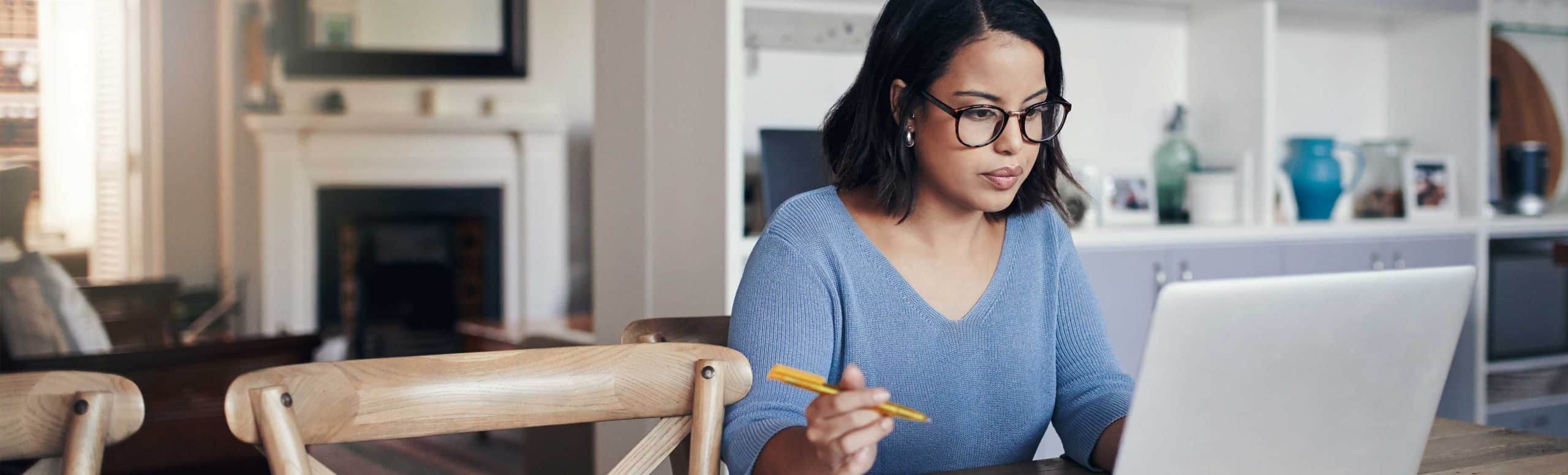 Woman using a laptop and holding a pencil