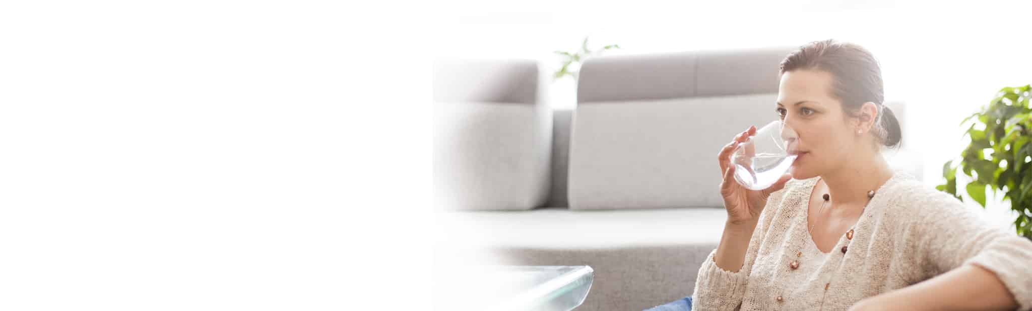 Person sitting down and drinking water from a glass