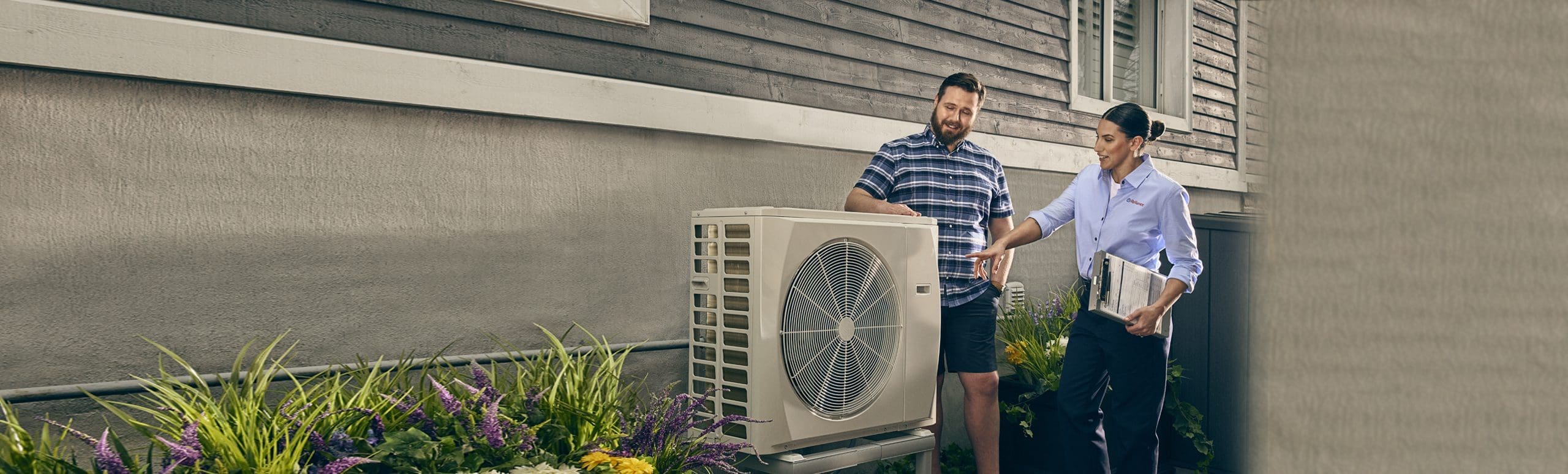 Heat pump outside of home with RHC technician and home owner